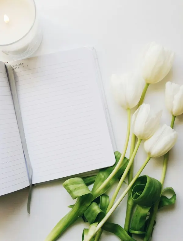 Tulipes blanches posées à côté d'un carnet ouvert